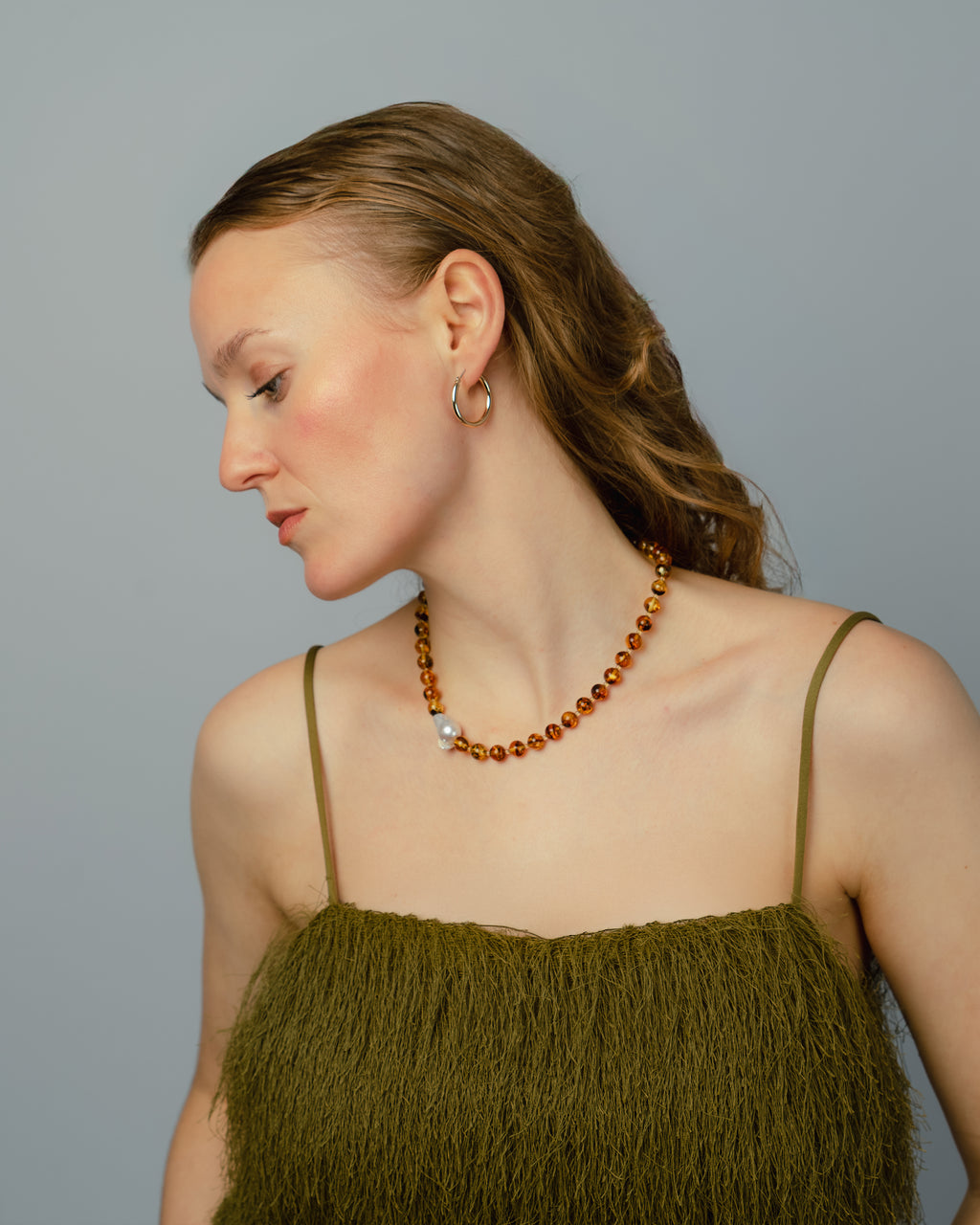 Woman wearing a green top and a beaded Amber necklace