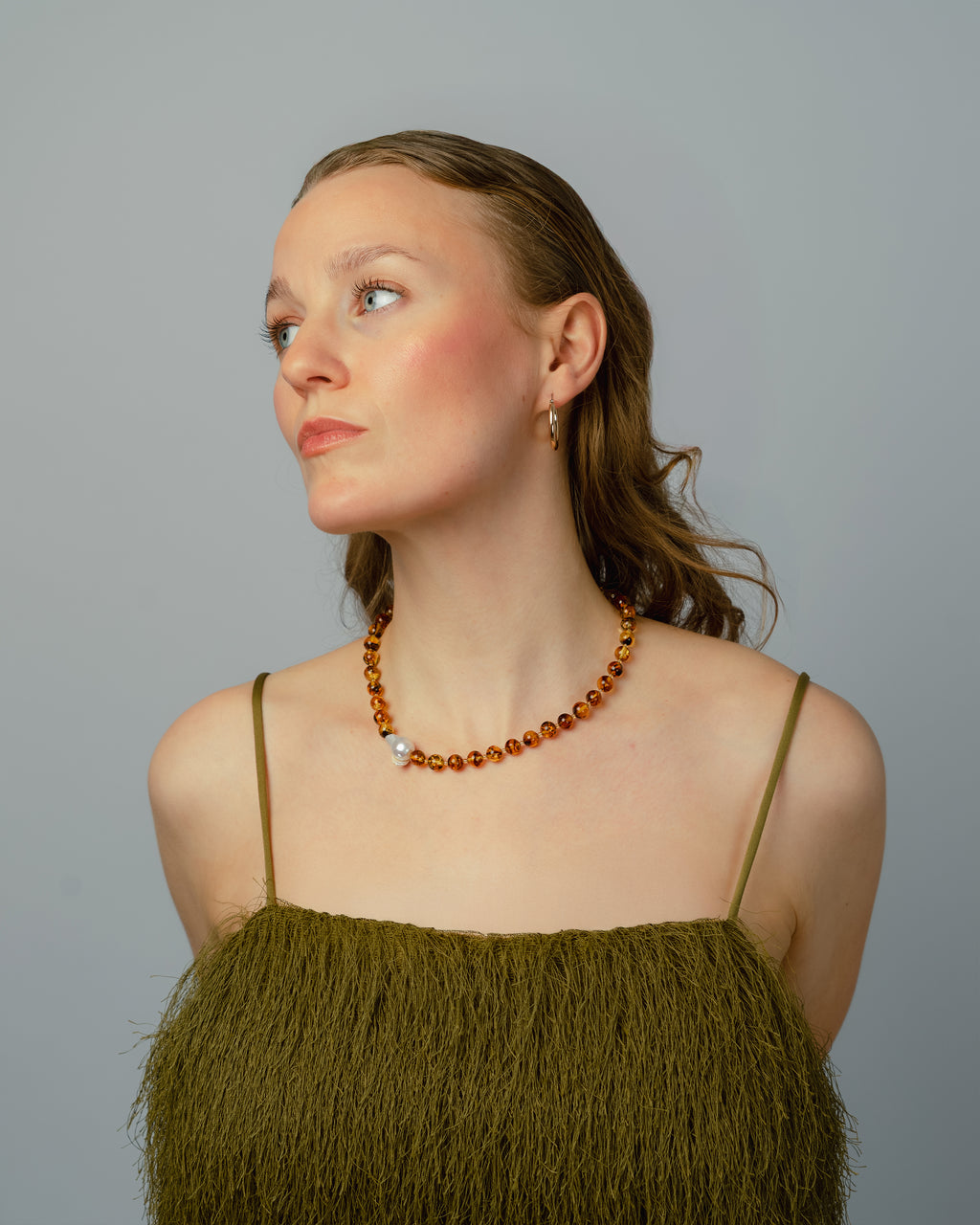 Woman wearing a green dress and amber beaded necklace