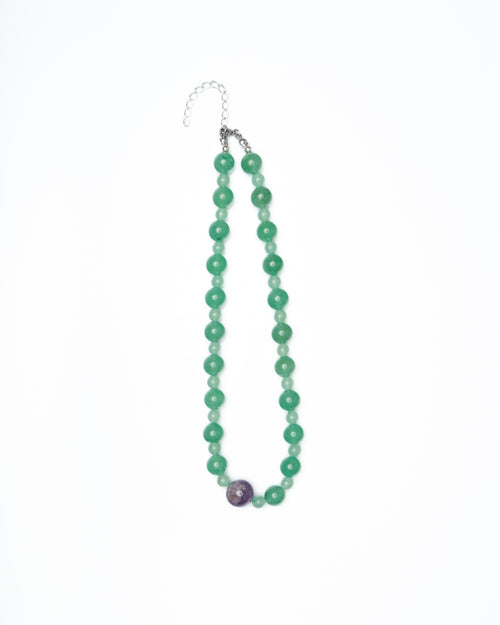 Green beaded necklace with a purple bead on a white background