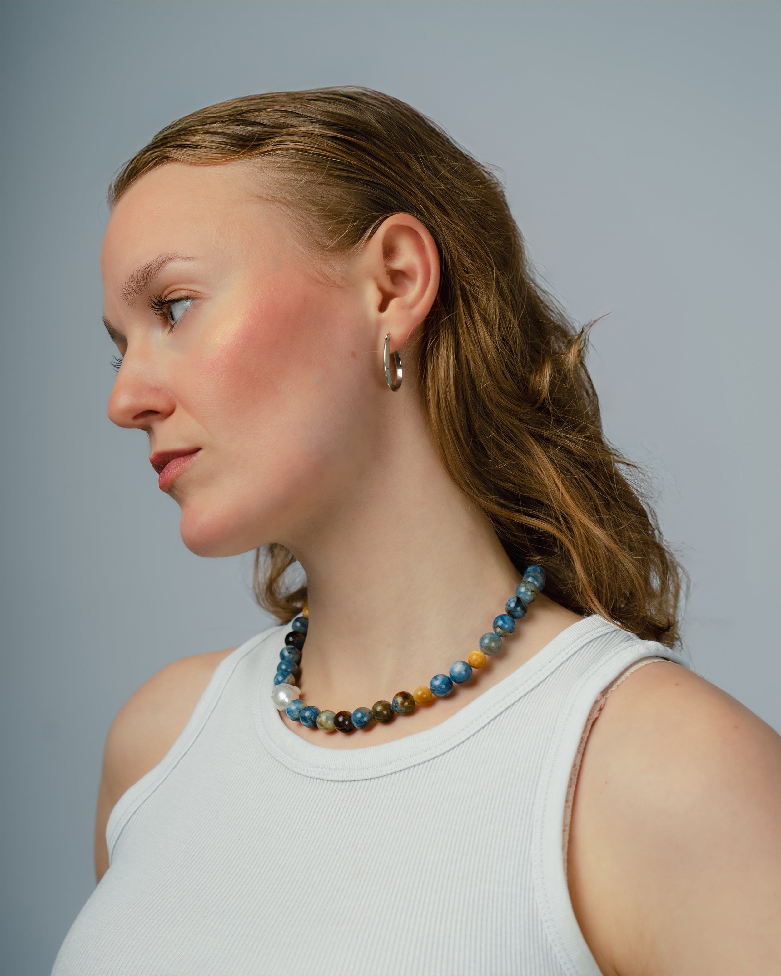 Woman wearing a colorful beaded necklace against a plain background