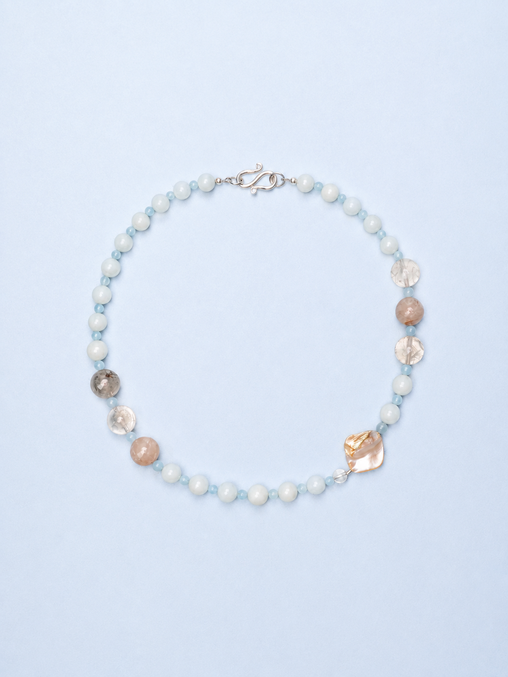 Necklace with pearls and shell-like beads on a light blue background