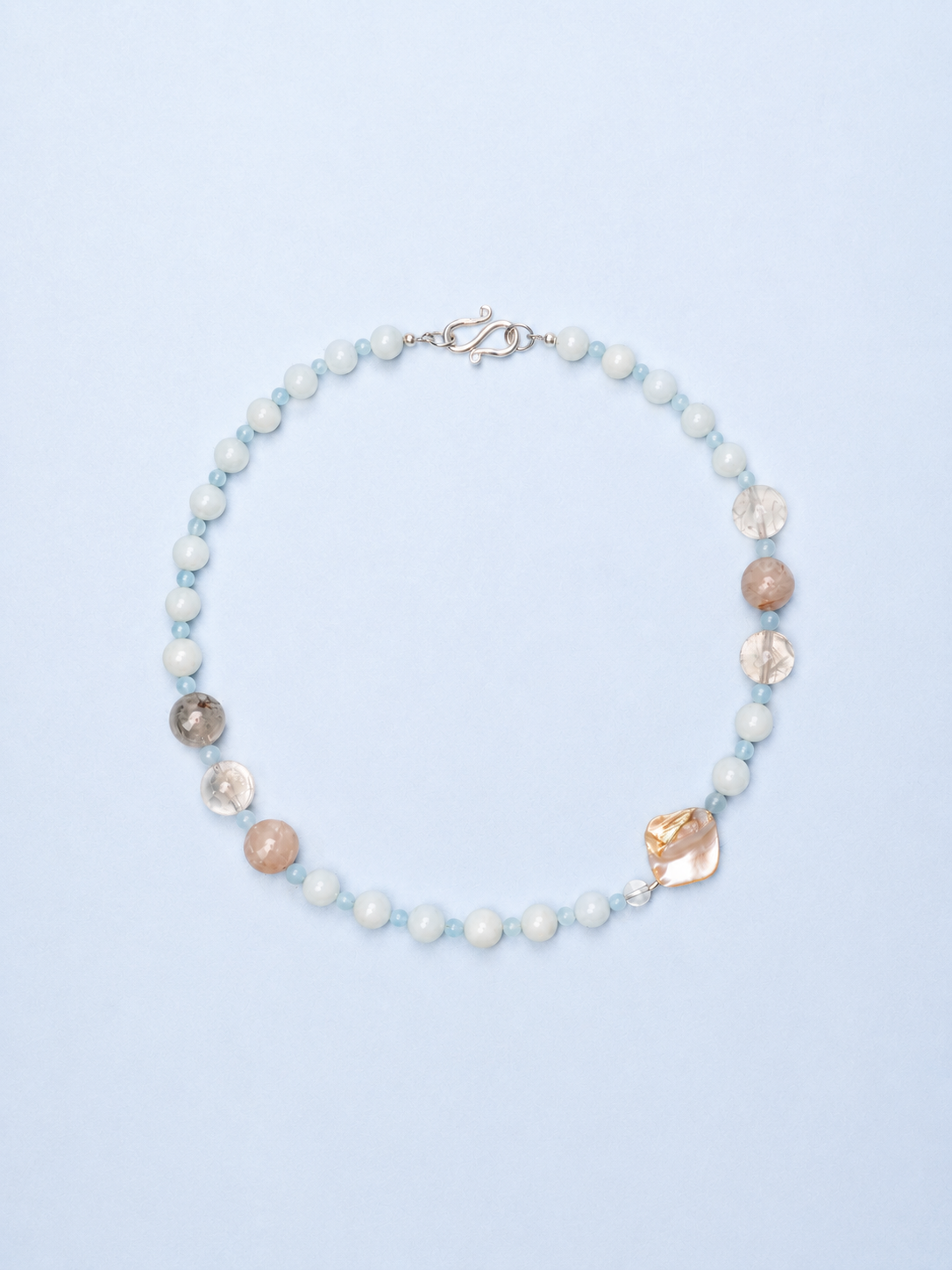 Necklace with pearls and shell-like beads on a light blue background
