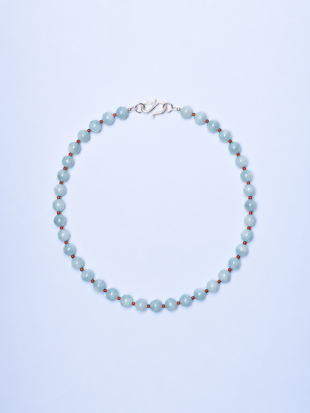 Pearl necklace with red beads on a light blue background
