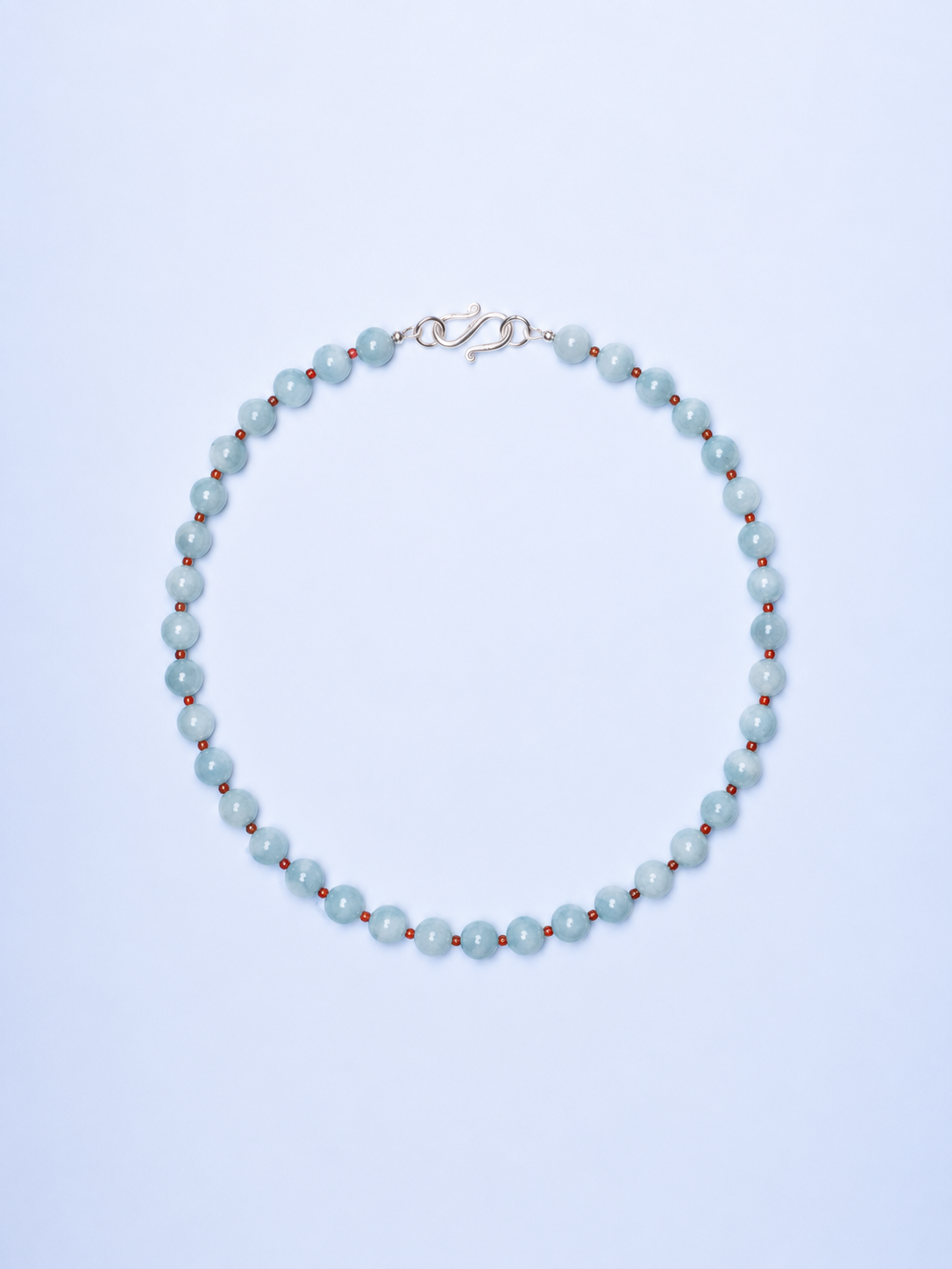 Pearl necklace with red beads on a light blue background