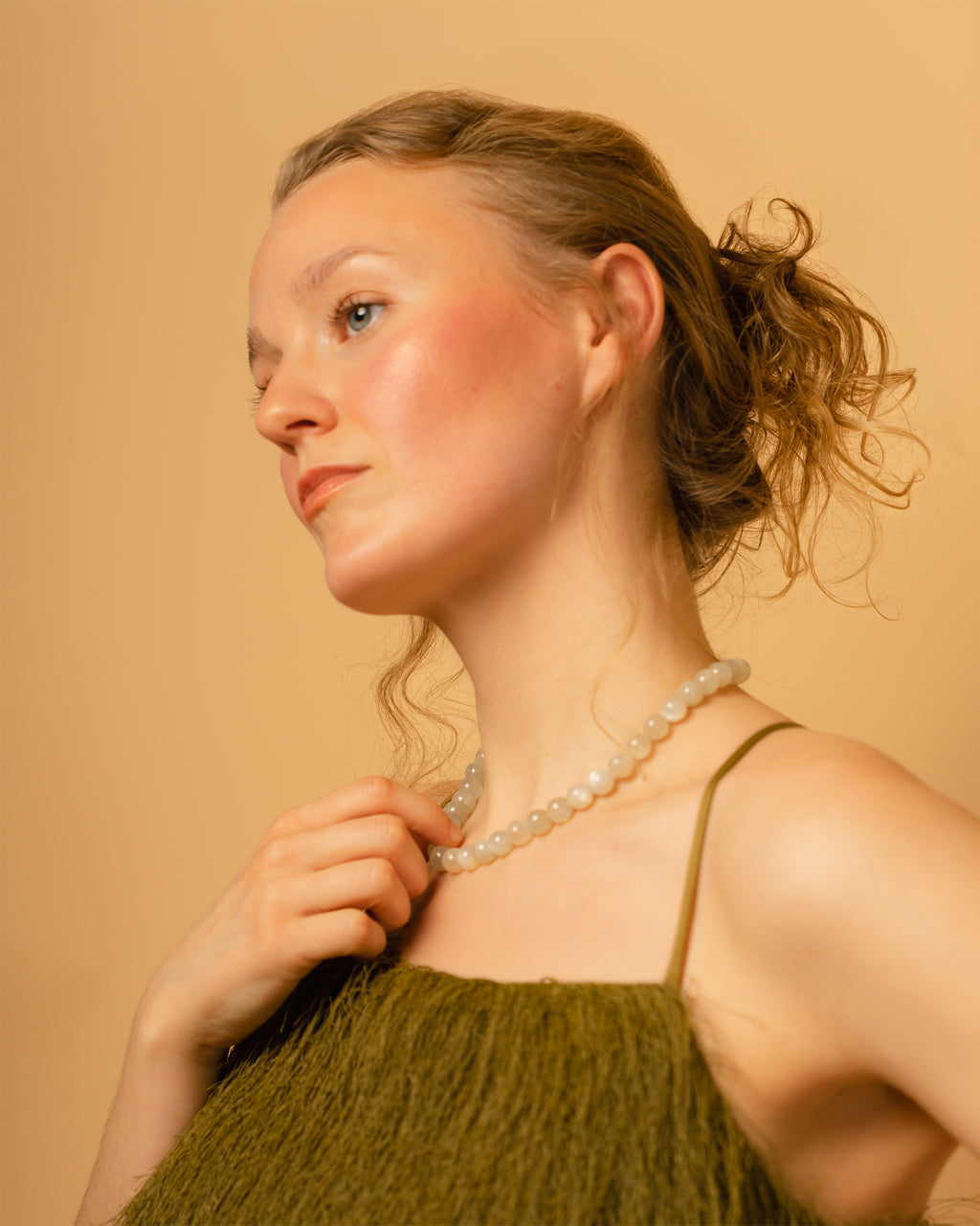 Woman wearing a green dress and moonstone necklace