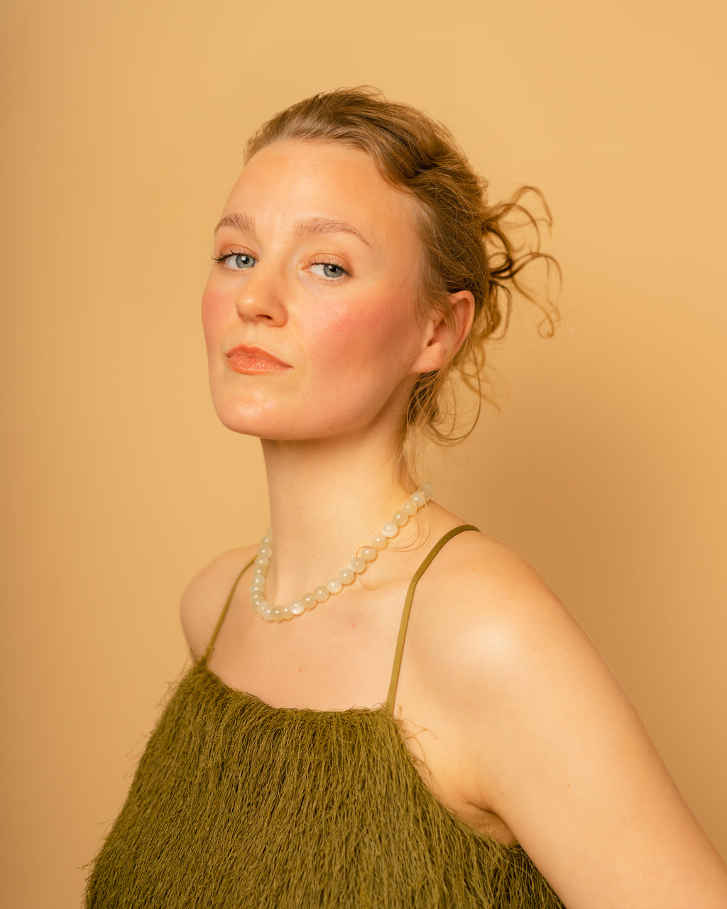 Woman wearing a green dress and moonstone necklace