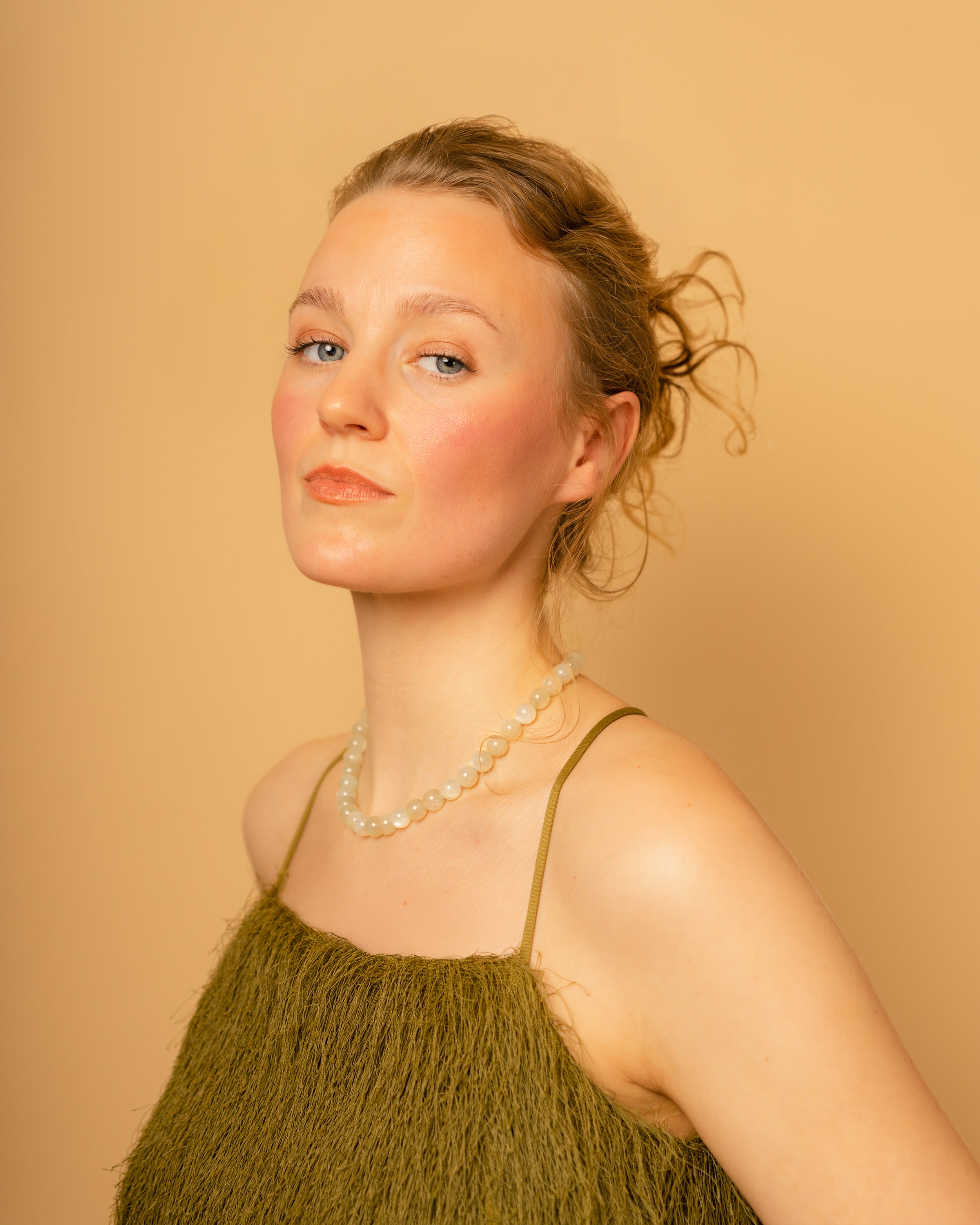 Woman wearing a green dress and moonstone necklace